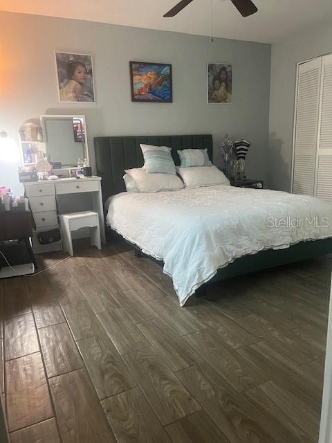 A bedroom features a dark upholstered bed, a white vanity, and wood-look tile flooring — 4016 LAKE BOULEVARD, CLEARWATER, FL