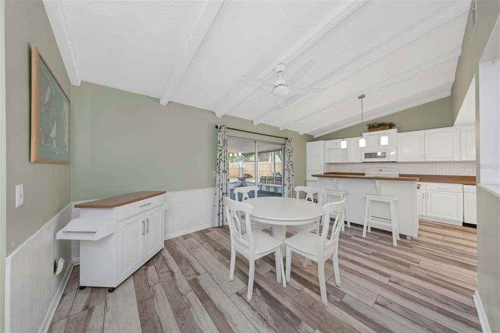 A dining area with a white table and chairs sits adjacent to a white kitchen — 17704 RIVENDEL ROAD, LUTZ, FL