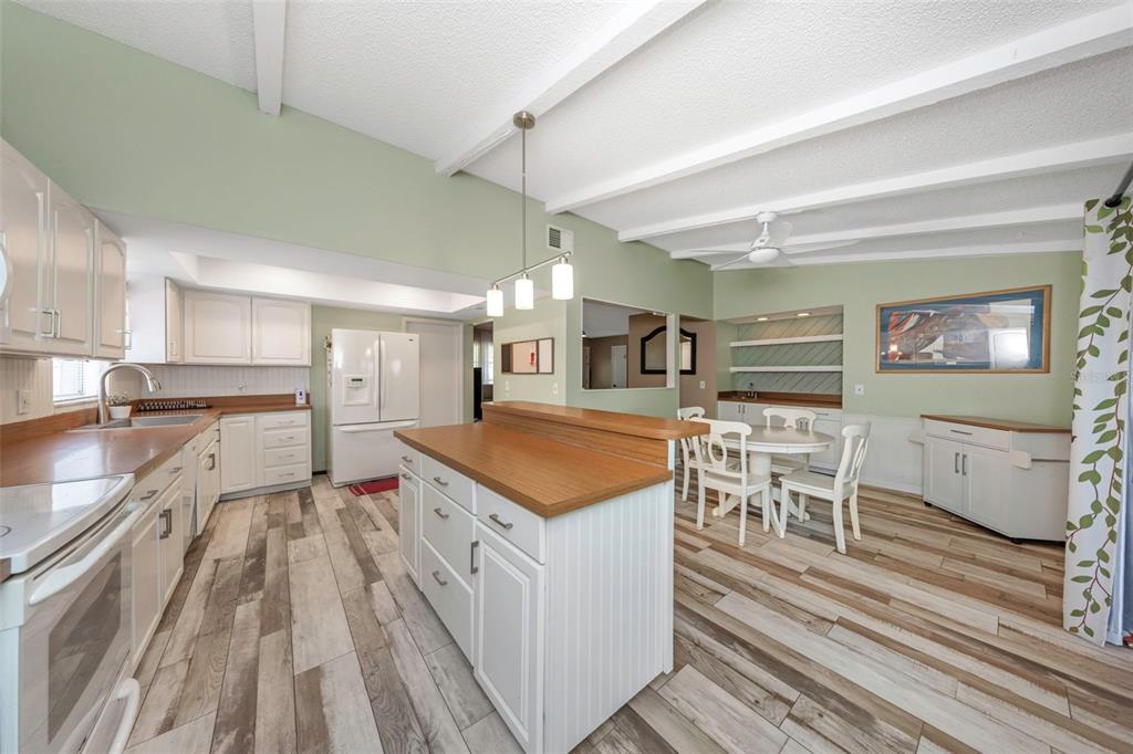 A kitchen with white cabinets, wood countertops, an island, and light-colored wood-look flooring — 17704 RIVENDEL ROAD, LUTZ, FL