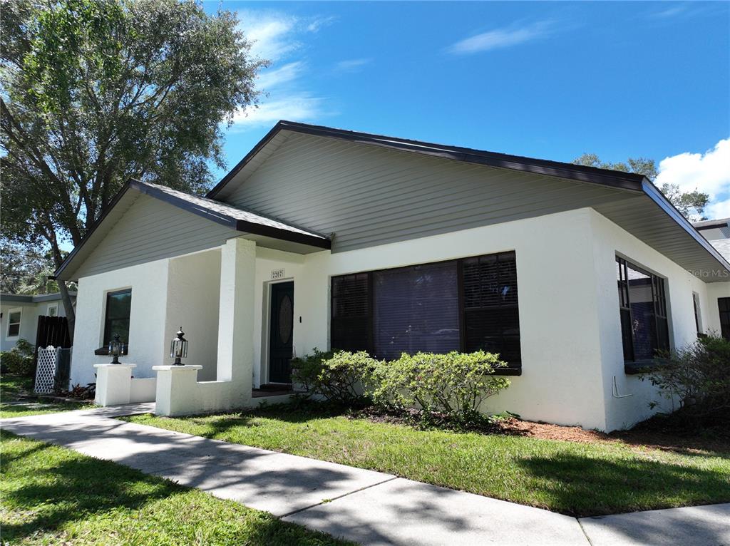 A single-story house with white stucco walls, gray siding, and a concrete walkway — 2207 W OHIO AVENUE, TAMPA, FL