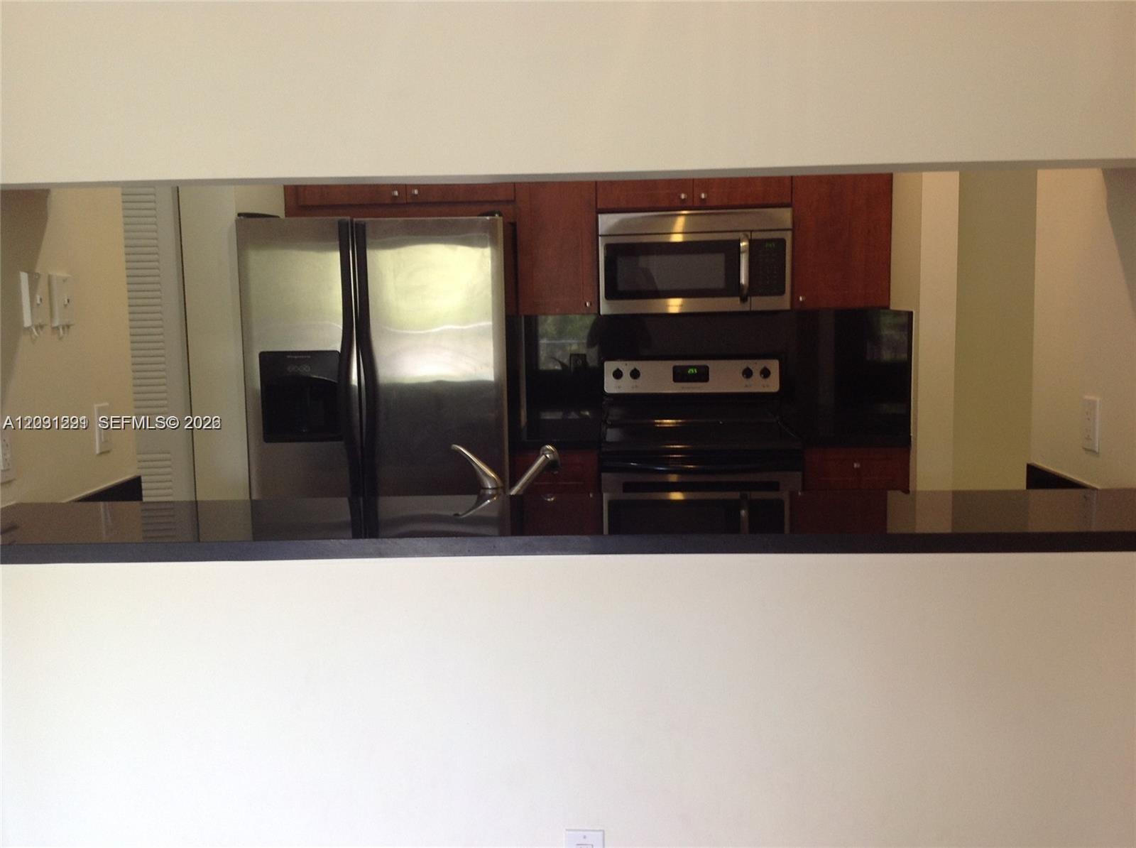 A kitchen features stainless steel appliances, dark wood cabinets, and a black countertop — 10610 SW 158th Ct # 303, Miami FL 33196, MIAMI, FL