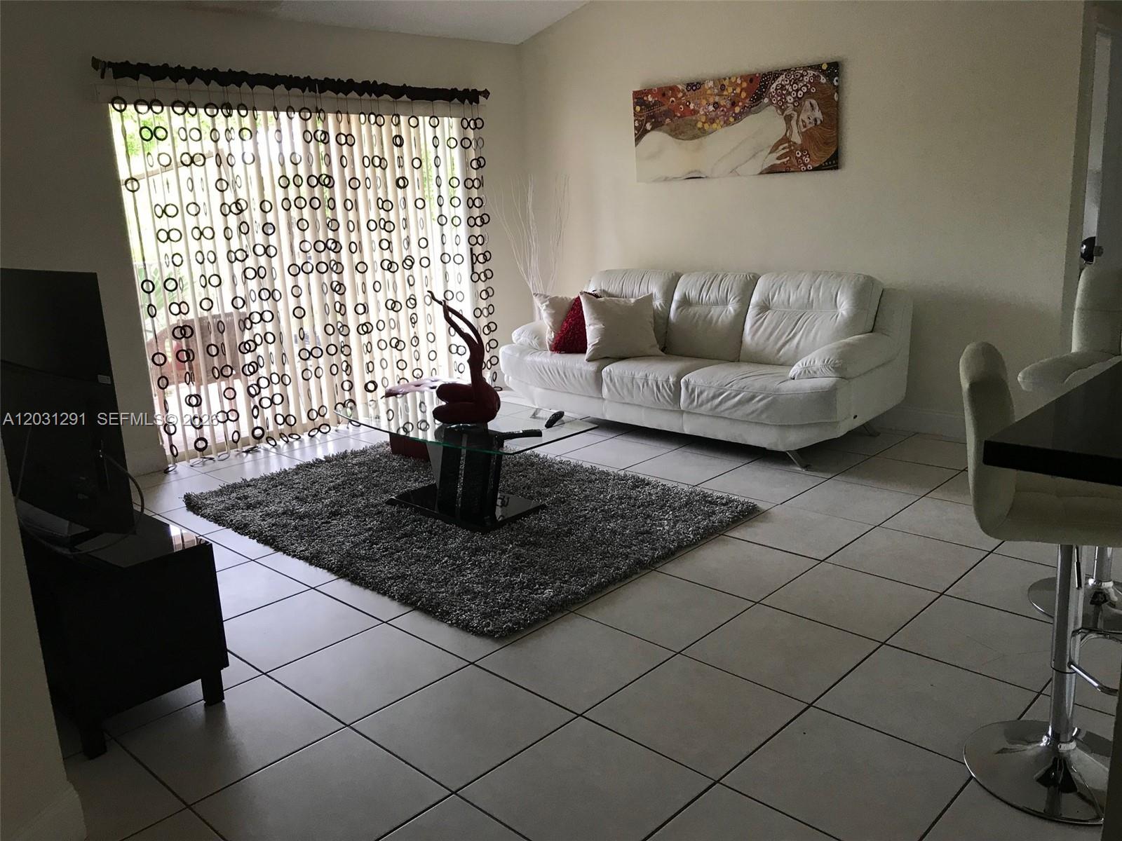 A living room features a white sofa, a glass coffee table, and a gray rug — 10610 SW 158th Ct # 303, Miami FL 33196, MIAMI, FL