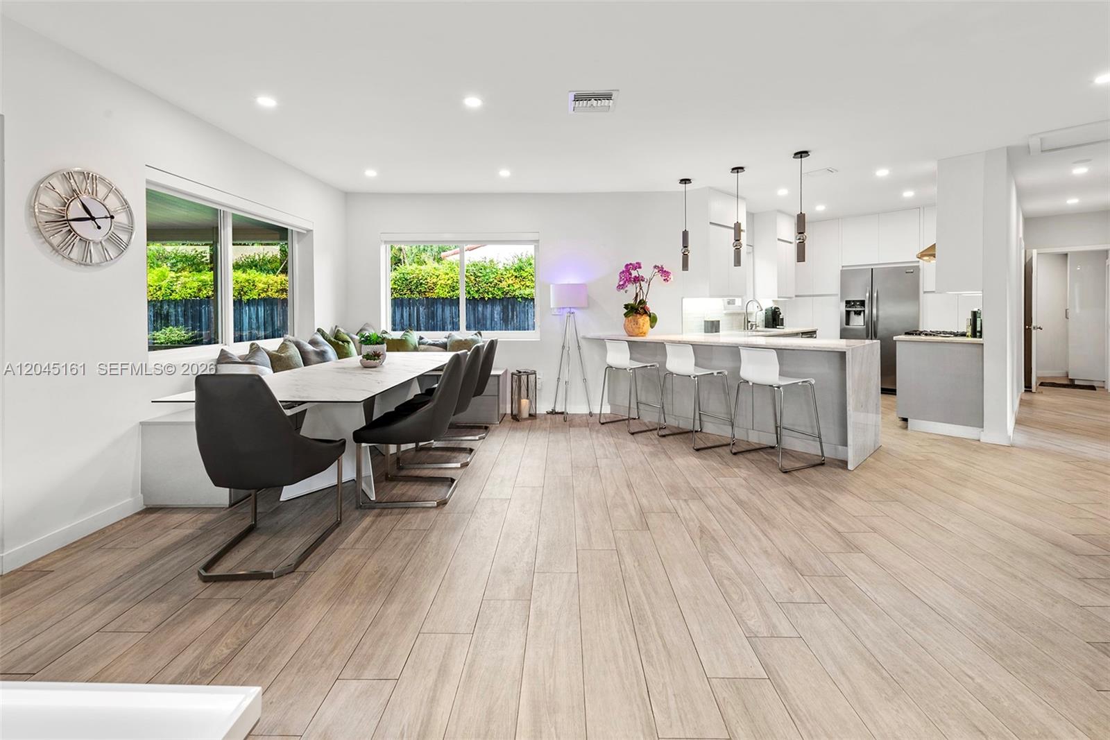 A modern open-concept dining area and kitchen feature light wood floors and white cabinetry — 1724 71st St, Miami Beach FL 33141, MIAMI BEACH, FL