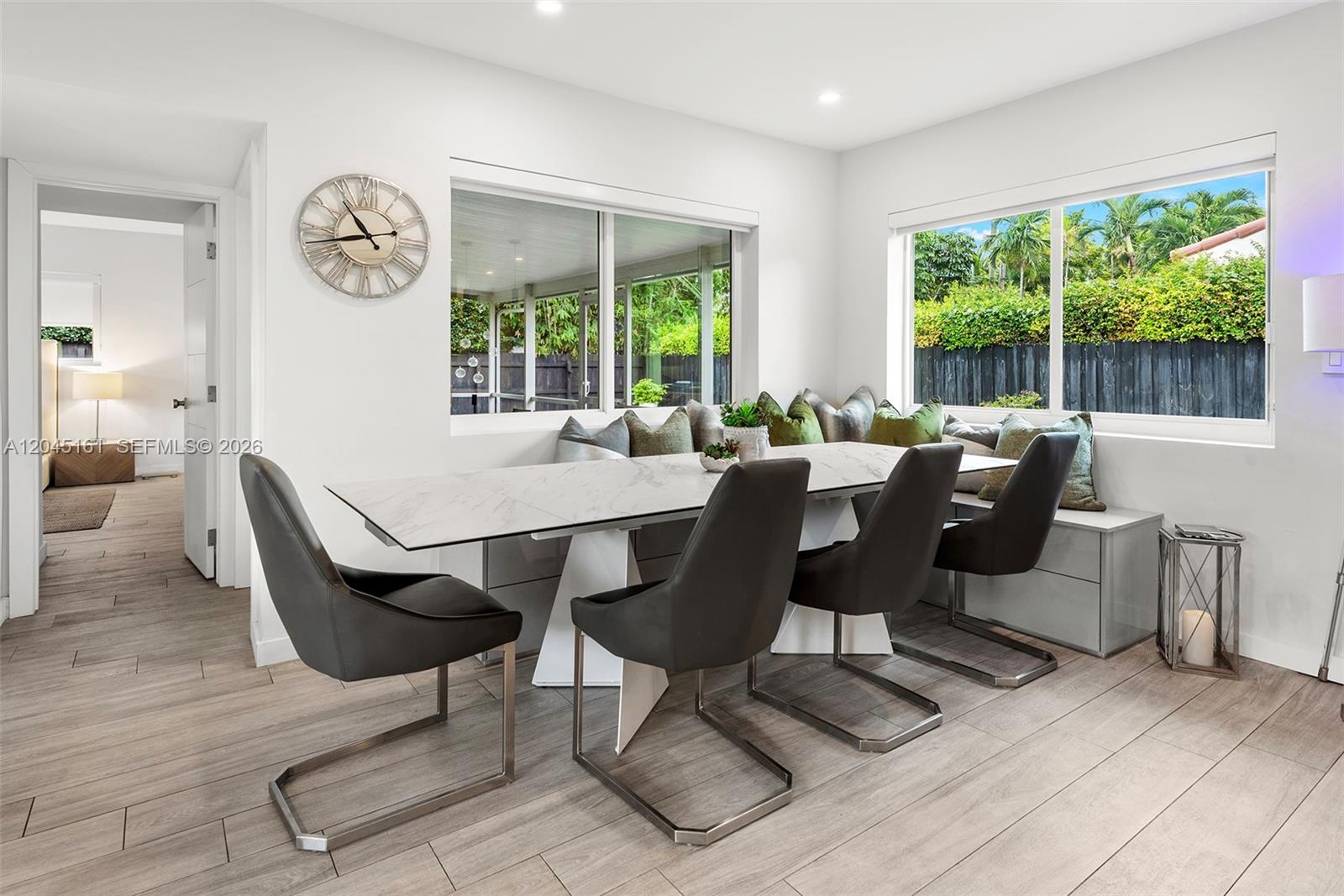 A dining area features a marble-top table, modern chairs, and built-in bench seating by windows — 1724 71st St, Miami Beach FL 33141, MIAMI BEACH, FL