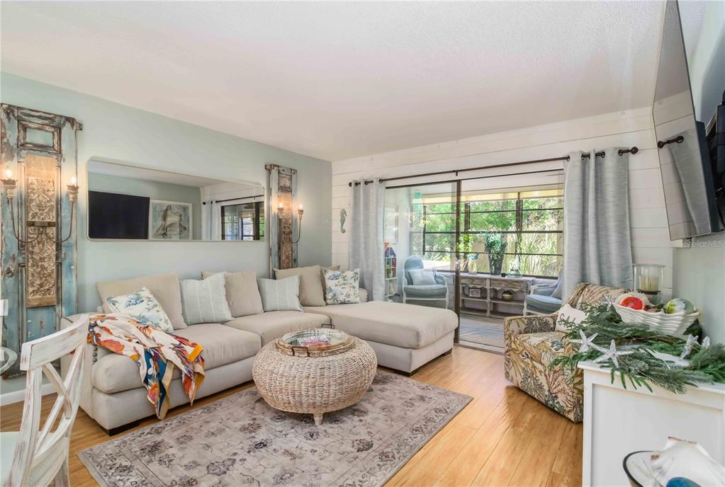 A living room features a sectional sofa, a wicker coffee table, and a large mirror — 218 PINENEEDLE DRIVE UNIT 218, BRADENTON, FL
