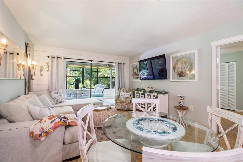 A coastal-themed living and dining area features a sectional sofa, glass table, and sliding doors — 218 PINENEEDLE DRIVE UNIT 218, BRADENTON, FL