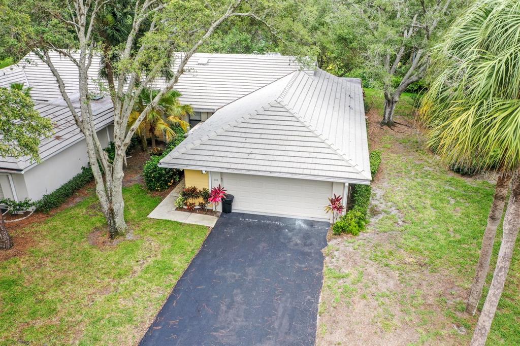 An aerial view of a single-story house with a light-colored tile roof and asphalt driveway — 243 SOUTHAMPTON LANE UNIT 273, VENICE, FL