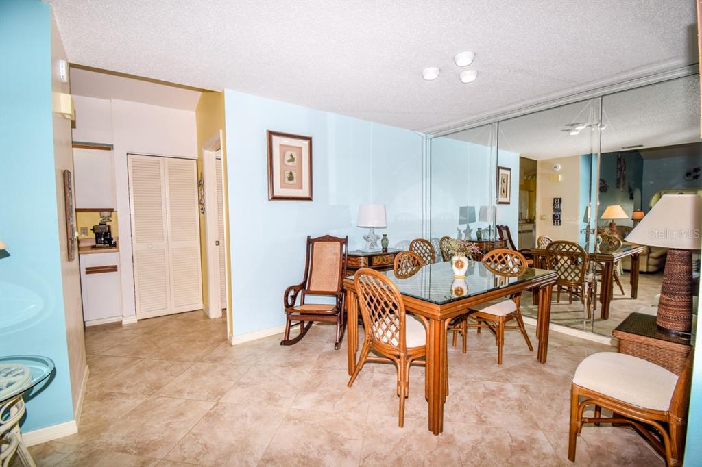 A dining room features a glass-topped table, rattan chairs, tile flooring, and a mirrored wall — 243 SOUTHAMPTON LANE UNIT 273, VENICE, FL