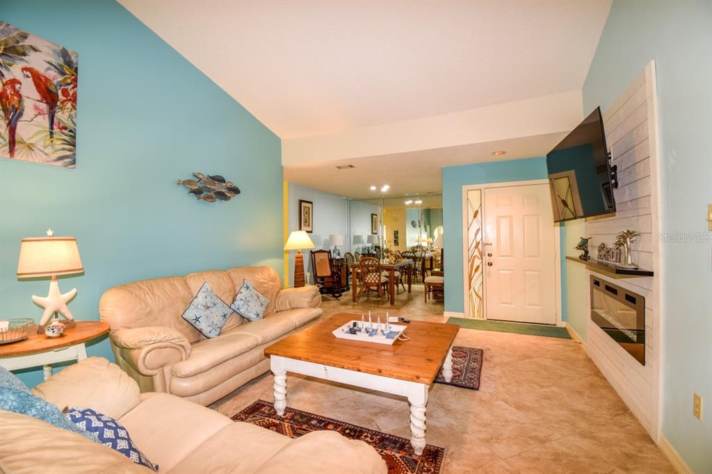 A living room features light blue walls, a beige sofa, a wooden coffee table, and a fireplace — 243 SOUTHAMPTON LANE UNIT 273, VENICE, FL