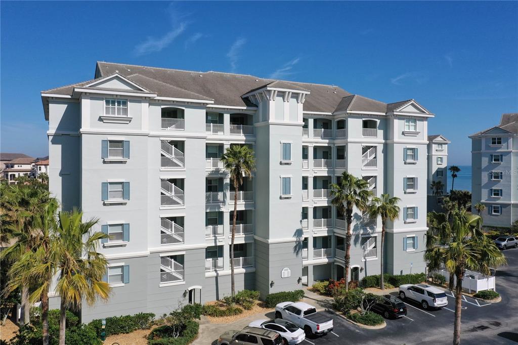 An exterior view of a multi-story apartment building with palm trees and a parking lot — 400 CINNAMON BEACH WAY UNIT 324, PALM COAST, FL