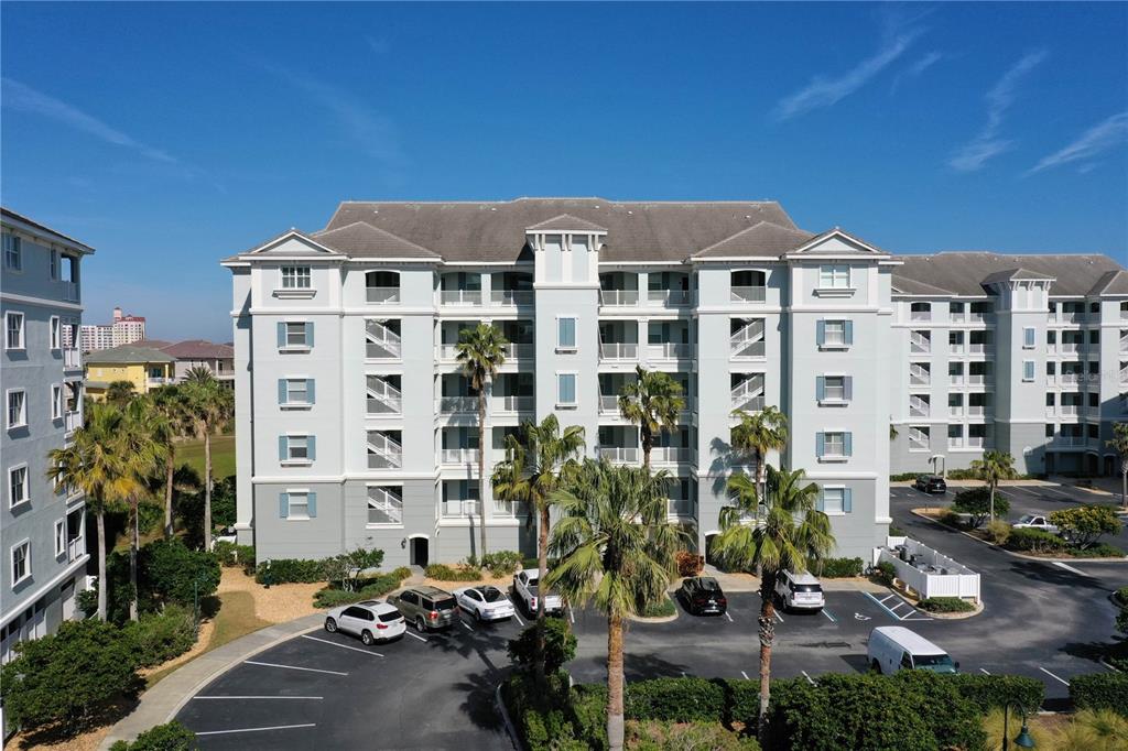 An exterior view of a multi-story apartment building with a parking lot and palm trees — 400 CINNAMON BEACH WAY UNIT 324, PALM COAST, FL