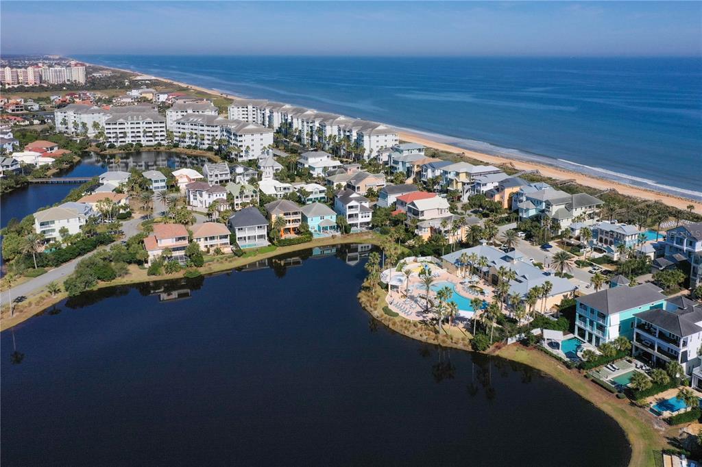 An aerial view shows a coastal community with houses, a pool, and a large lake — 400 CINNAMON BEACH WAY UNIT 324, PALM COAST, FL