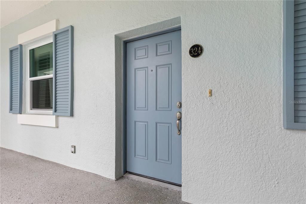 A light blue front door with a house number sits on a textured exterior wall — 400 CINNAMON BEACH WAY UNIT 324, PALM COAST, FL