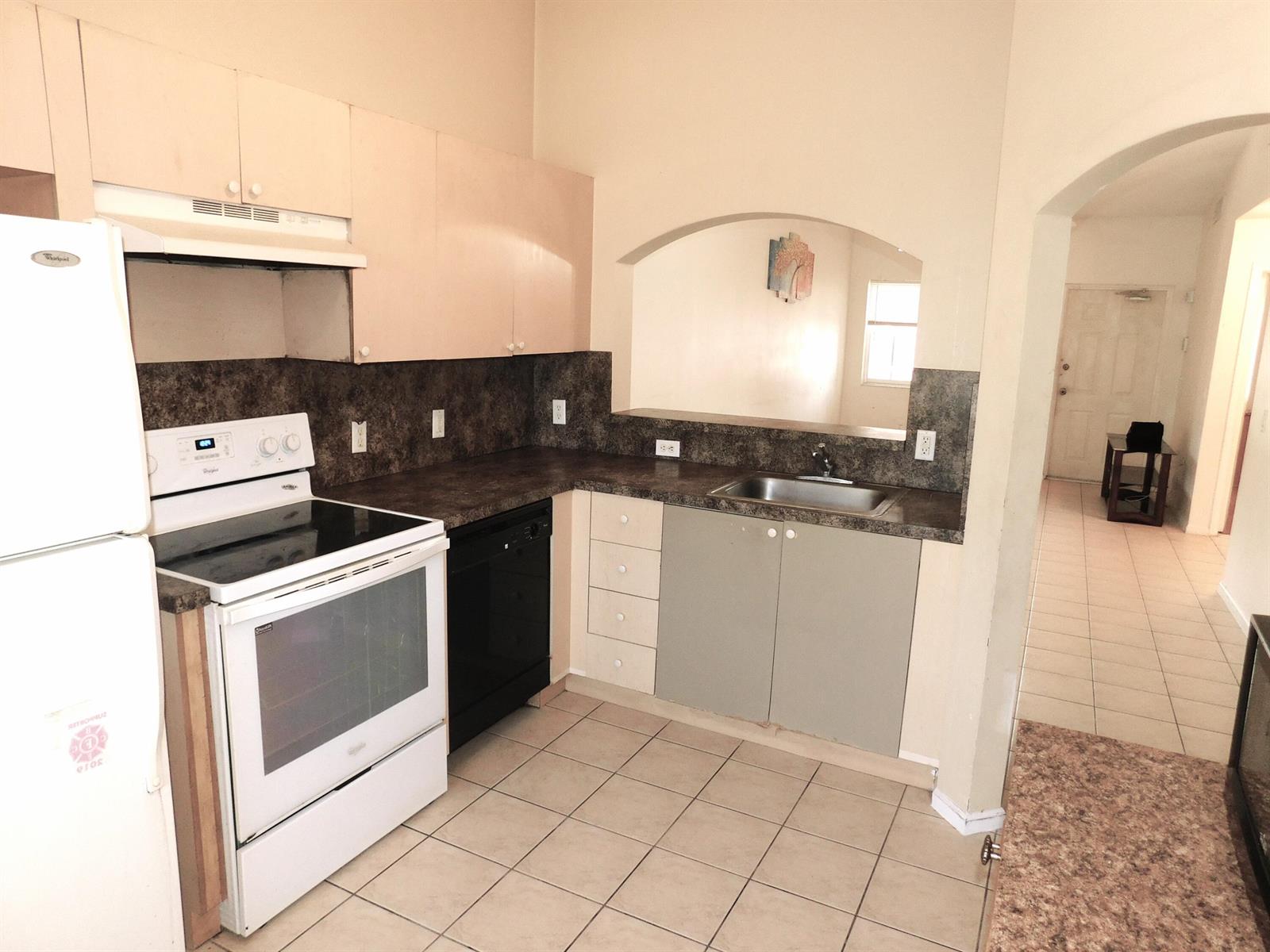 A kitchen with light cabinets, dark countertops, a white stove, and a pass-through window — 3800 N Jog Road # 204, West Palm Beach FL 33411, WEST PALM BEACH, FL