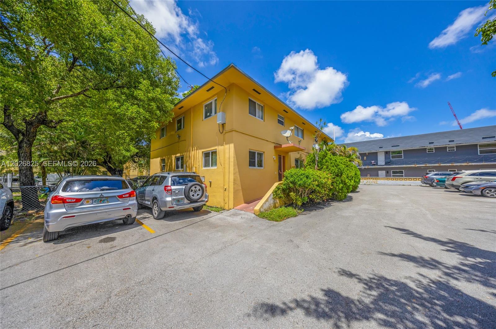 A yellow two-story apartment building sits next to a parking lot with several parked cars — 840 NW 4th St, Miami FL 33128, MIAMI, FL