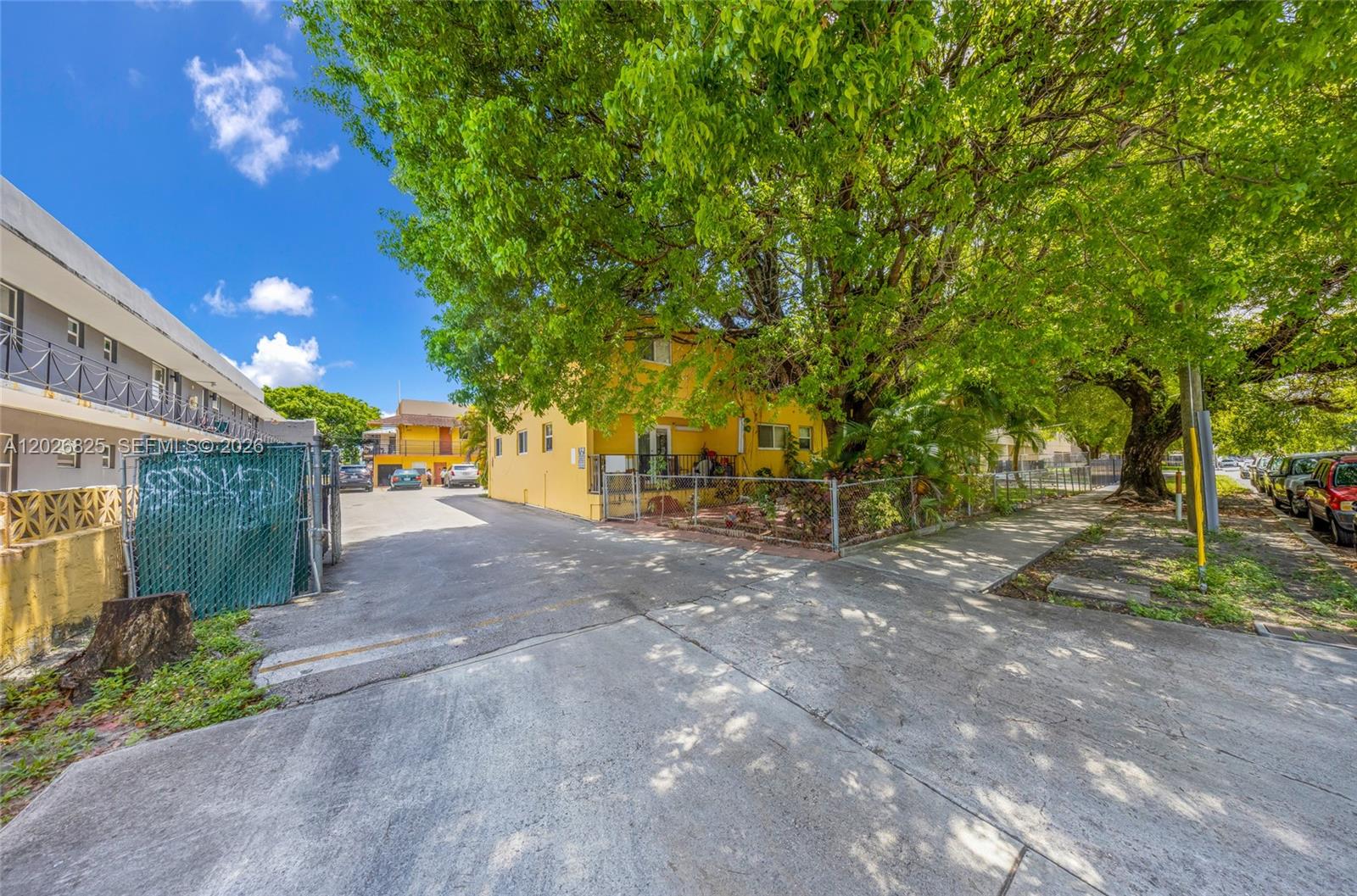 A yellow two-story building stands behind a chain-link fence next to a paved driveway — 840 NW 4th St, Miami FL 33128, MIAMI, FL