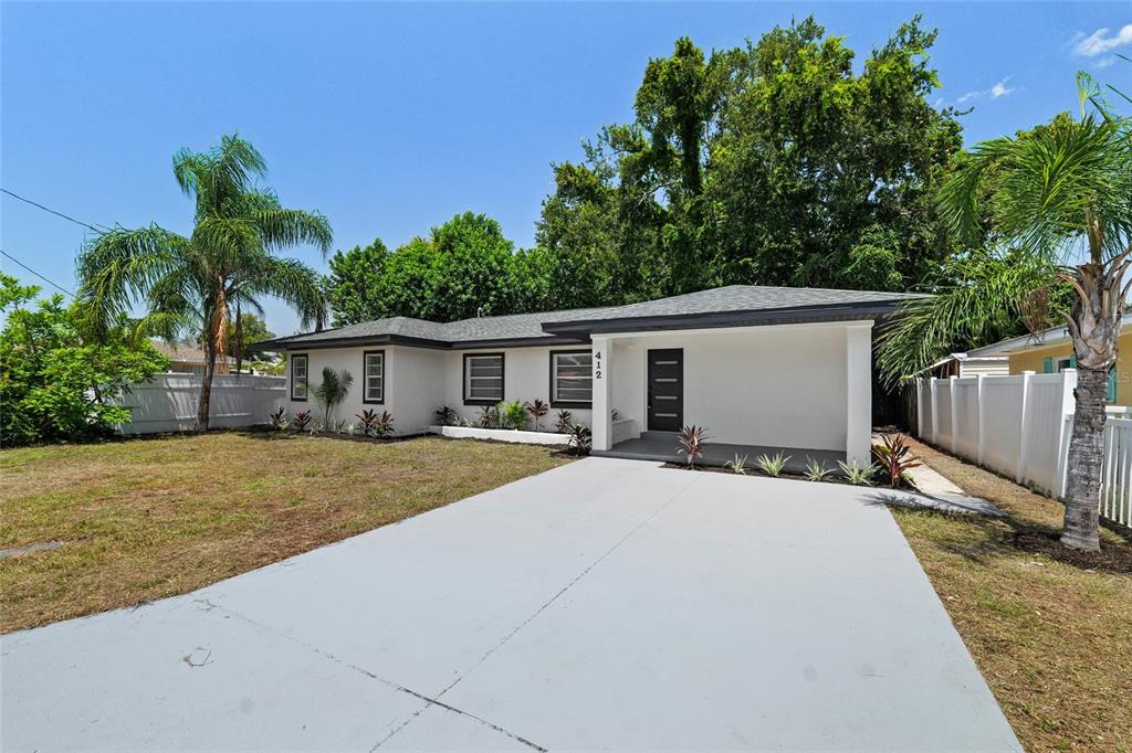 A single-story white house with a gray roof, a concrete driveway, and palm trees — 412 20TH AVENUE W, PALMETTO, FL