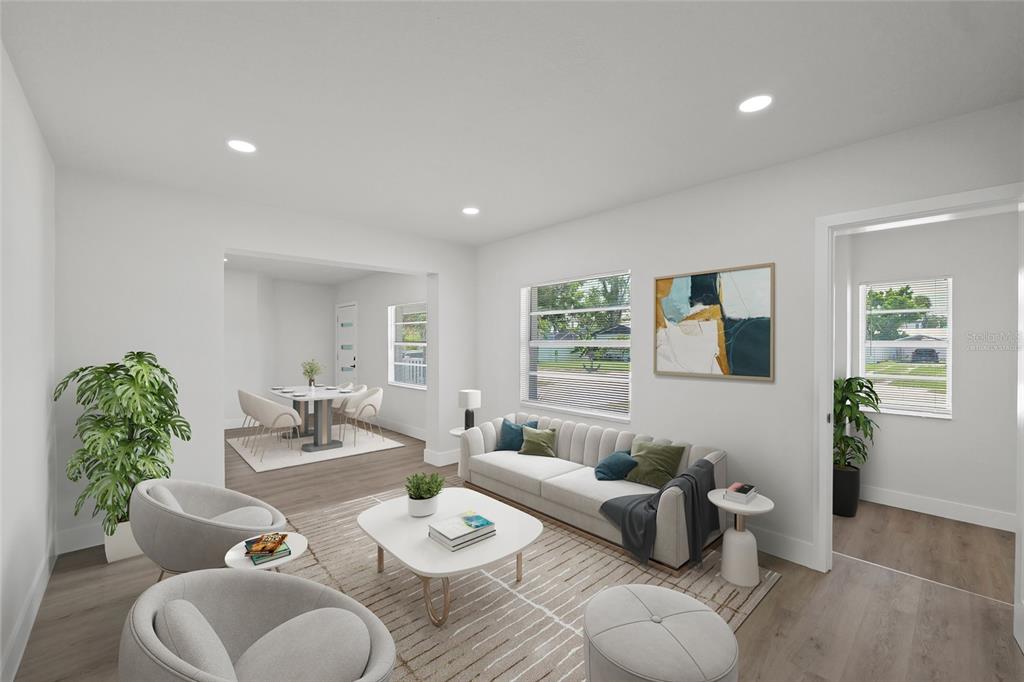 This is a virtually staged living room with light wood floors and a dining area — 412 20TH AVENUE W, PALMETTO, FL
