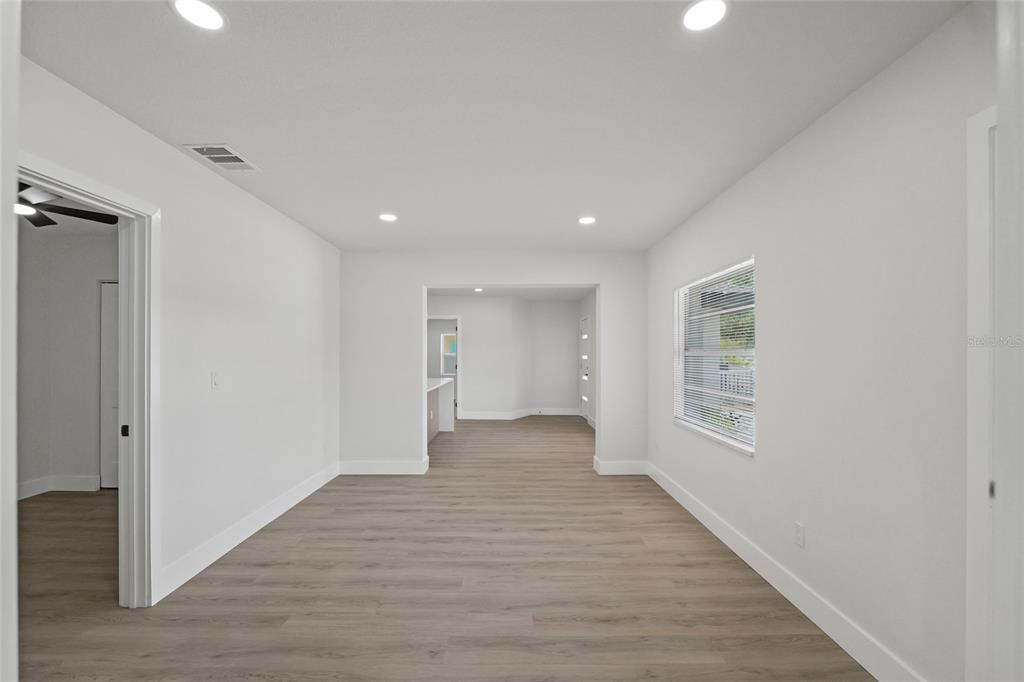 A bright, empty room with light wood-look flooring, white walls, and recessed ceiling lights — 412 20TH AVENUE W, PALMETTO, FL