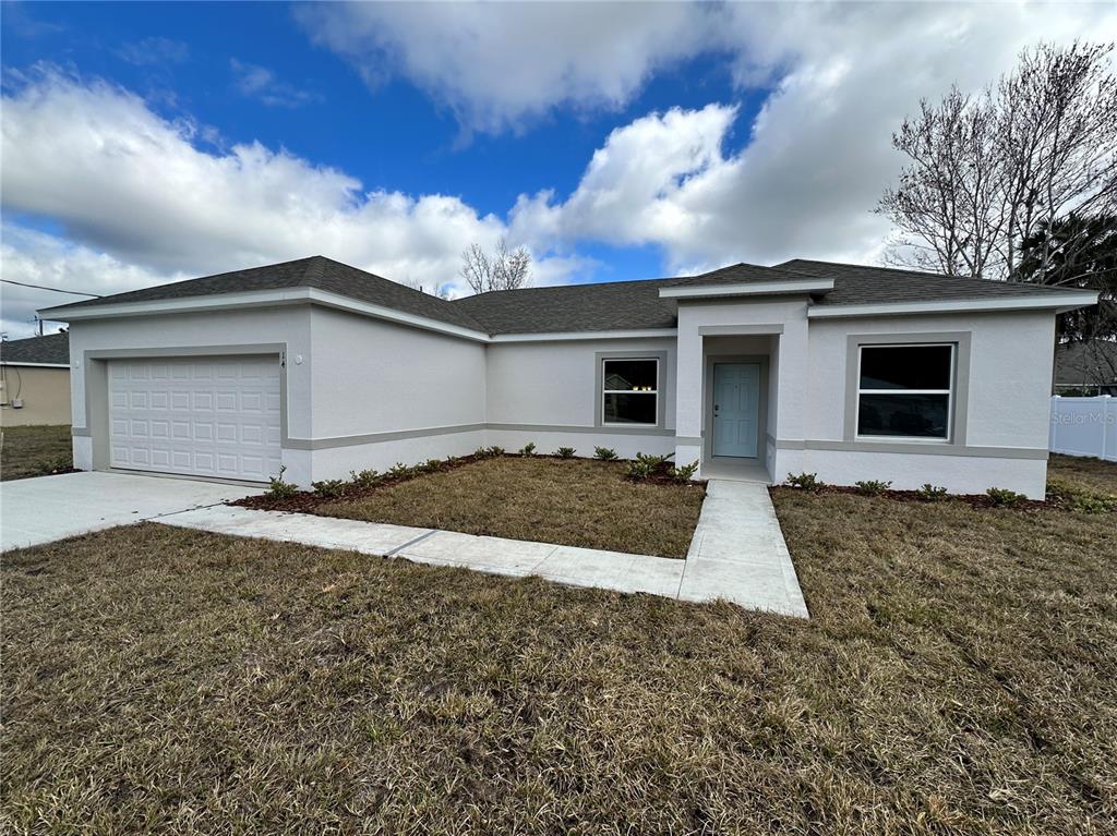 A single-story house with a white stucco exterior, a two-car garage, and a light blue door — 14 LONDONDERRY DRIVE, PALM COAST, FL