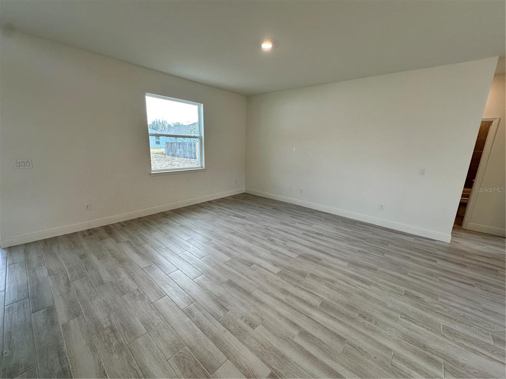 An empty room features light-colored wood-look tile flooring, white walls, and a single window — 14 LONDONDERRY DRIVE, PALM COAST, FL