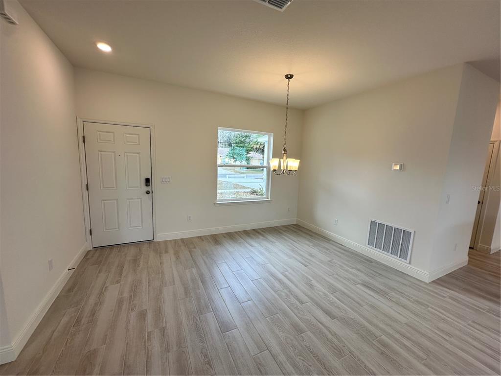 An empty dining room features light wood-look tile flooring, a chandelier, and a white door — 14 LONDONDERRY DRIVE, PALM COAST, FL