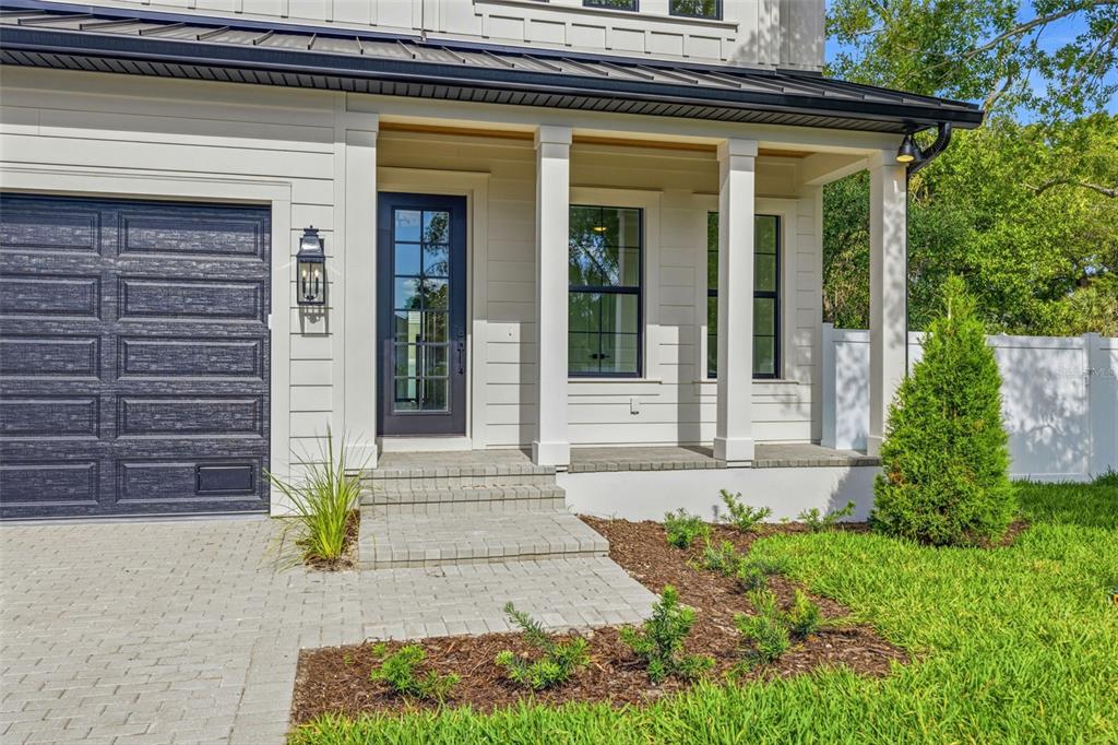 A modern house exterior features white horizontal siding, a dark garage door, and a covered porch — 2936 W ROGERS AVENUE, TAMPA, FL