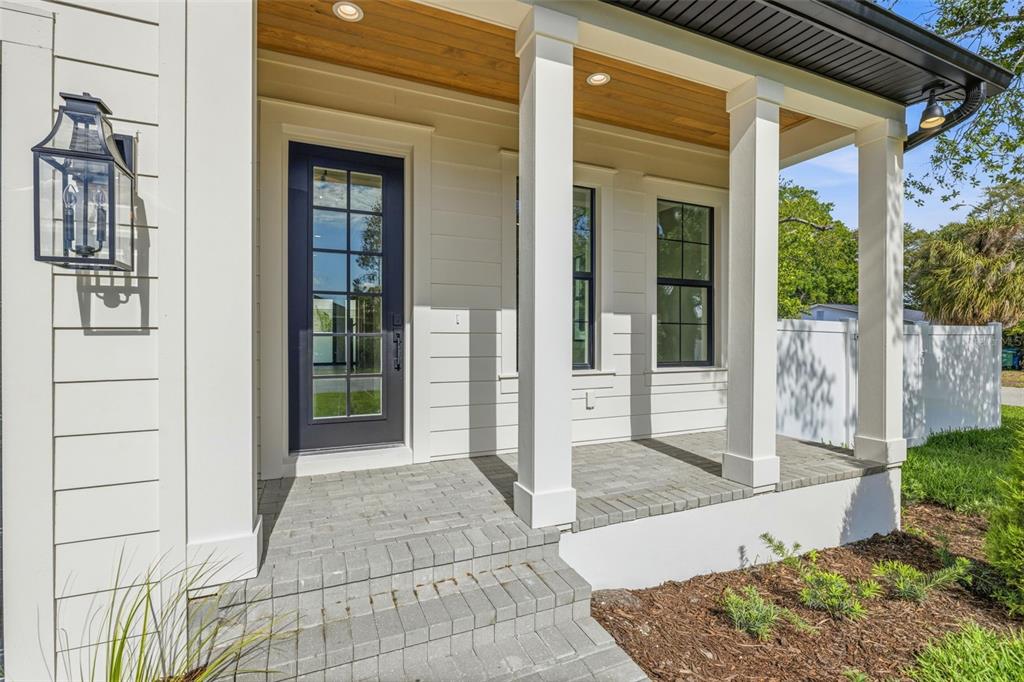 A covered front porch features white columns, a dark blue glass door, and paver steps — 2936 W ROGERS AVENUE, TAMPA, FL