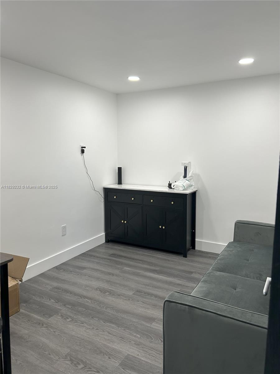 A room features gray wood-look flooring, white walls, a black cabinet, and a gray sofa — 3634 NW 36th St, Miami FL 33142, MIAMI, FL