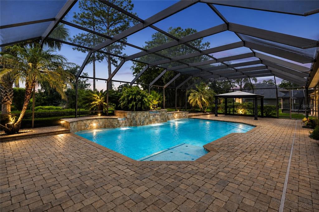 A screened-in patio features a swimming pool with stone water features and paver decking — 1413 COURSE VIEW, ORANGE PARK, FL