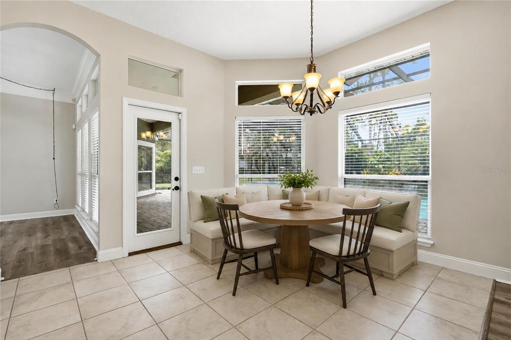 A breakfast nook features a corner banquette, a round wooden table, and a chandelier — 1413 COURSE VIEW, ORANGE PARK, FL