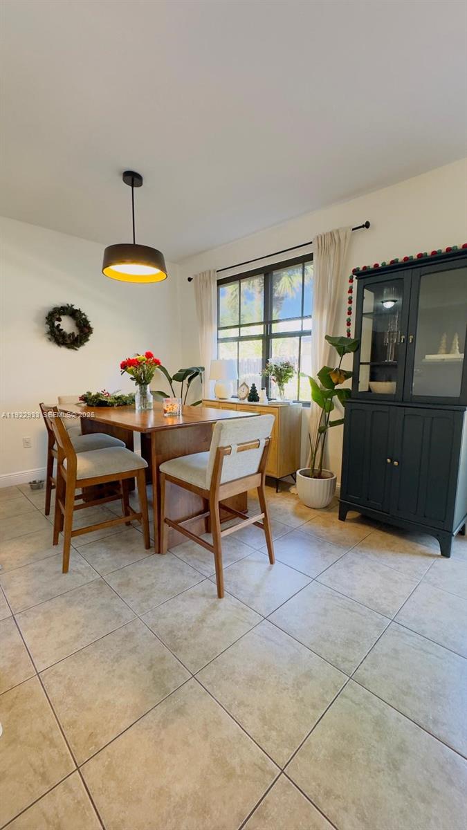 A dining room features a wooden table, four chairs, a dark cabinet, and a pendant light — 10131 NW 10th St, Miami FL 33172, MIAMI, FL