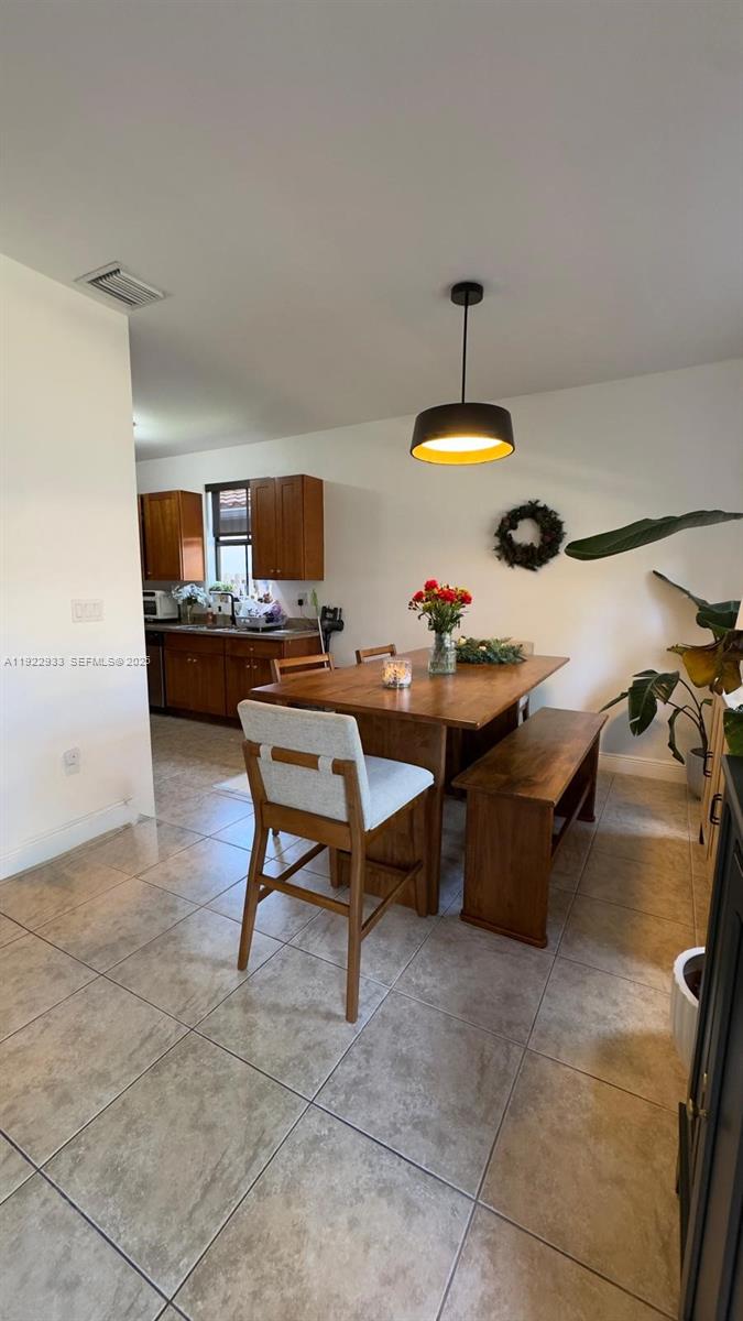 A dining area with a wooden table, bench, and chair sits adjacent to a kitchen — 10131 NW 10th St, Miami FL 33172, MIAMI, FL
