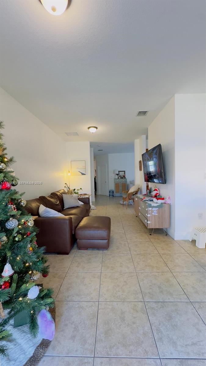 A living room features a brown leather sofa, a Christmas tree, and a wall-mounted television — 10131 NW 10th St, Miami FL 33172, MIAMI, FL
