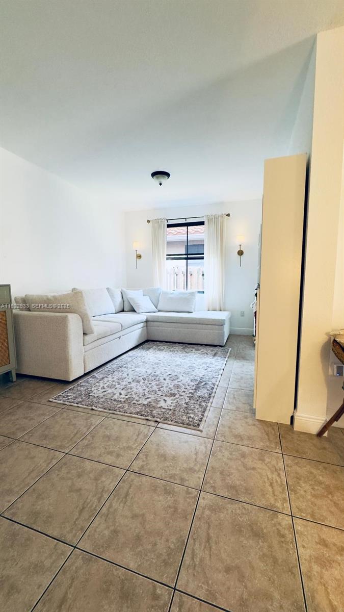 A living room features a light-colored sectional sofa, a patterned area rug, and tile flooring — 10131 NW 10th St, Miami FL 33172, MIAMI, FL