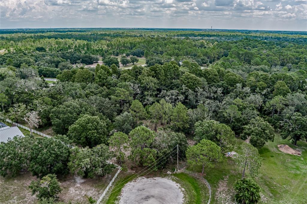 An aerial view shows a wooded lot with a white fence and a sandy clearing — 401 INDIAN MEADOW COURT, WIMAUMA, FL