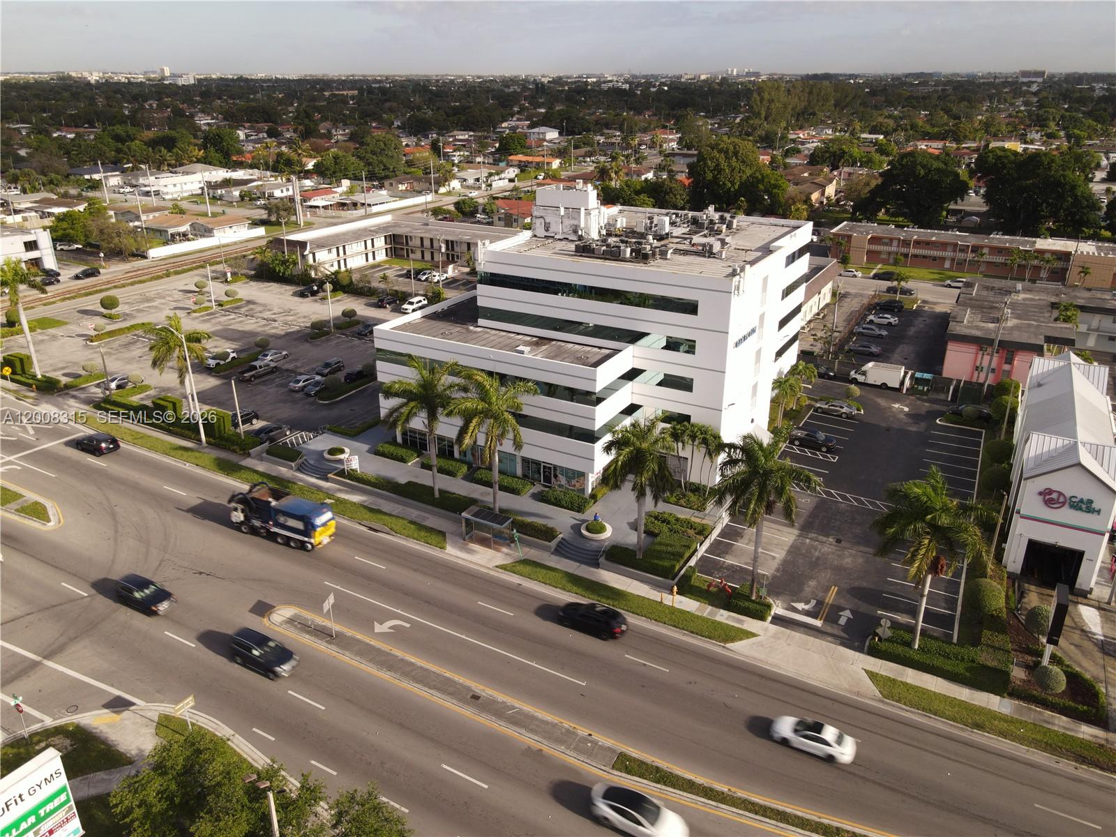 An aerial view shows a white multi-story office building surrounded by parking lots and palm trees — 7171 SW 24th St, Miami FL 33155, MIAMI, FL