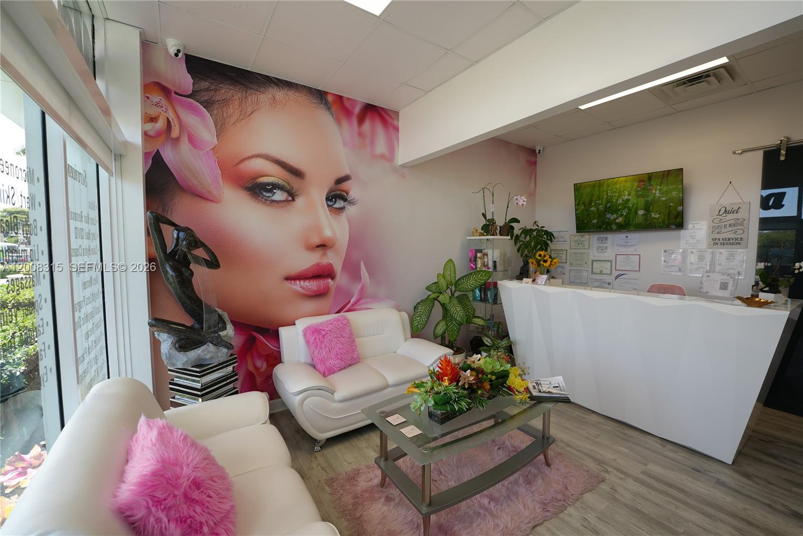 A spa reception area features white sofas, a glass coffee table, and a large wall mural — 7171 SW 24th St, Miami FL 33155, MIAMI, FL