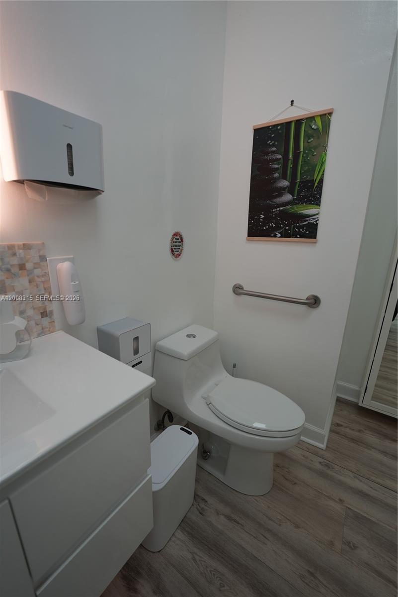 A modern bathroom features a white vanity, a toilet, a grab bar, and wall art — 7171 SW 24th St, Miami FL 33155, MIAMI, FL