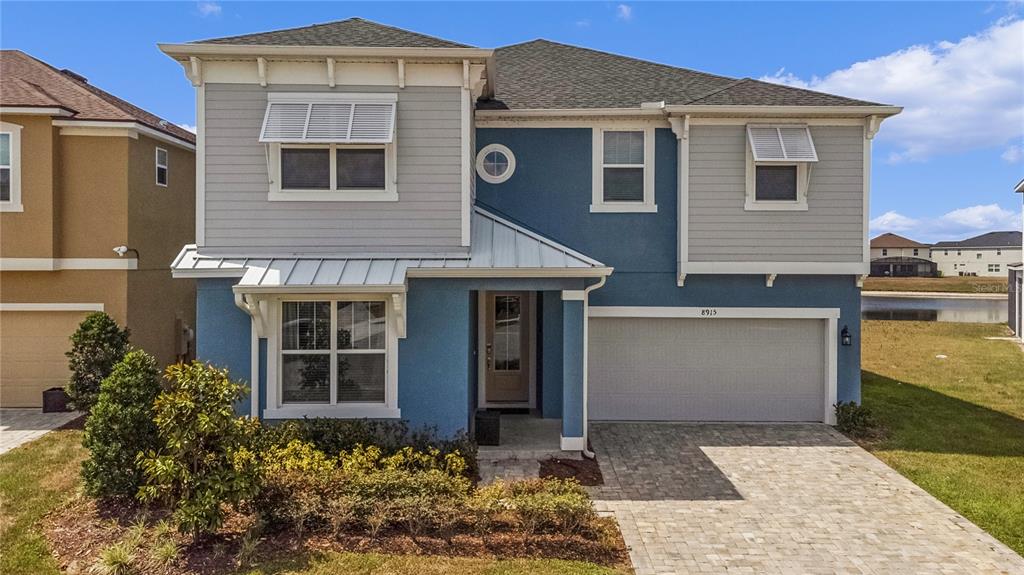 A two-story blue and gray house with a paved driveway and a front porch — 8915 TROPICAL HAVEN COURT, KISSIMMEE, FL