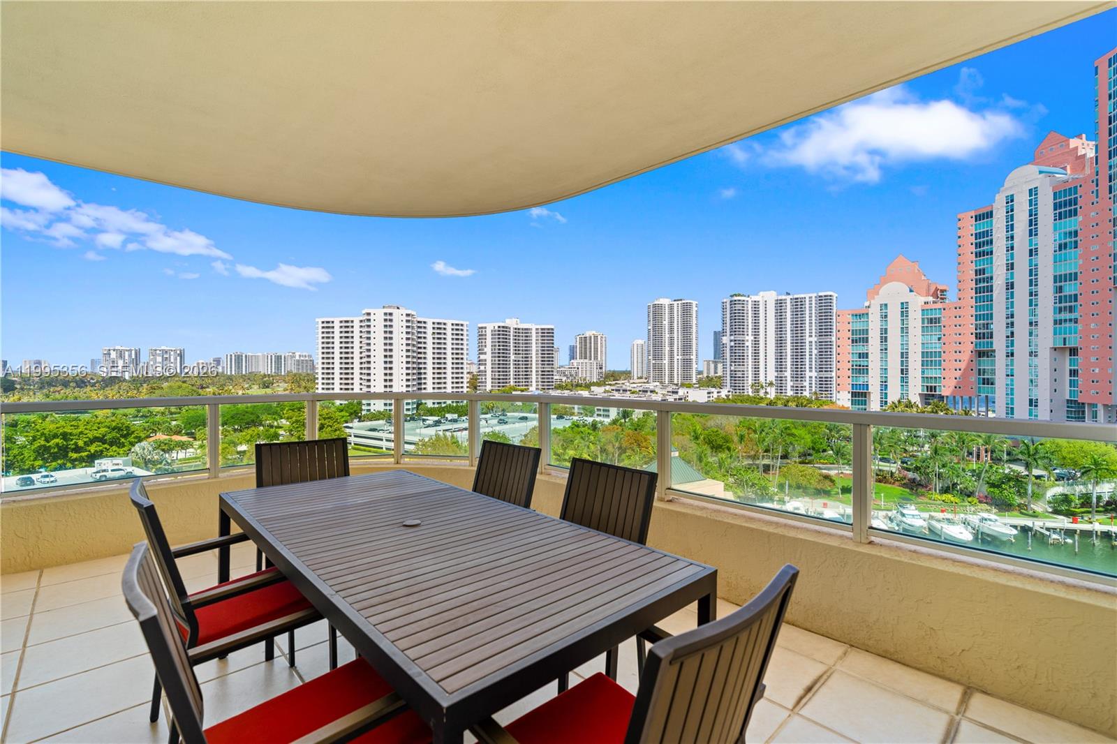 A balcony with a dining set overlooks a city skyline, a marina, and green space — 3340 NE 190th St # 1004, Aventura FL 33180, AVENTURA, FL
