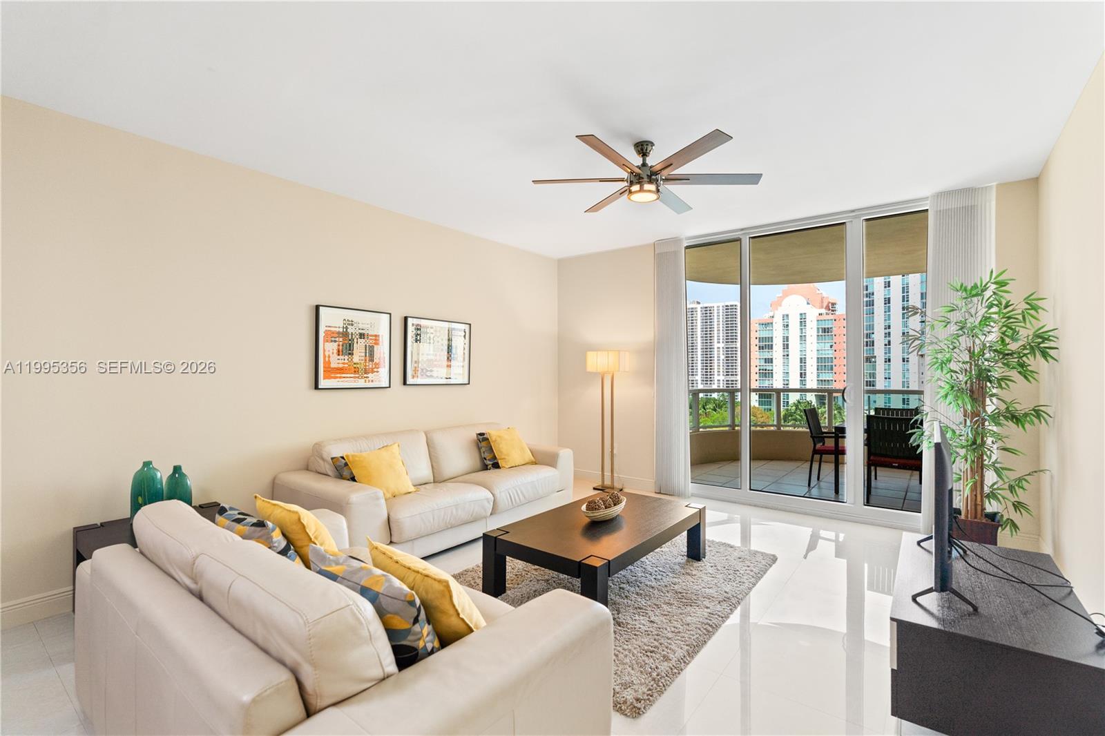 A living room features two beige sofas, a dark coffee table, and a balcony view — 3340 NE 190th St # 1004, Aventura FL 33180, AVENTURA, FL