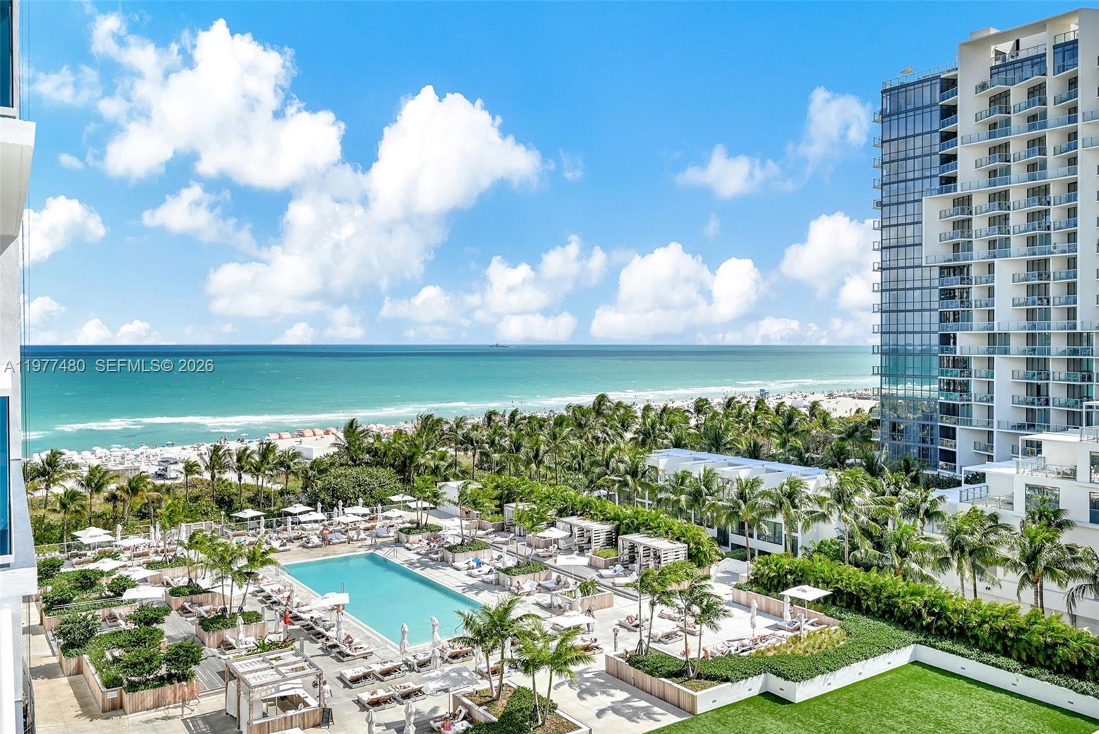 An elevated view shows a swimming pool, palm trees, a sandy beach, and the ocean — 2301 Collins Ave # 802, Miami Beach FL 33139, MIAMI BEACH, FL