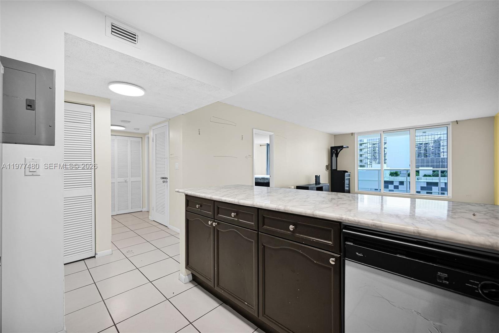 A kitchen island with dark cabinets and a marble countertop faces a living area — 2301 Collins Ave # 802, Miami Beach FL 33139, MIAMI BEACH, FL