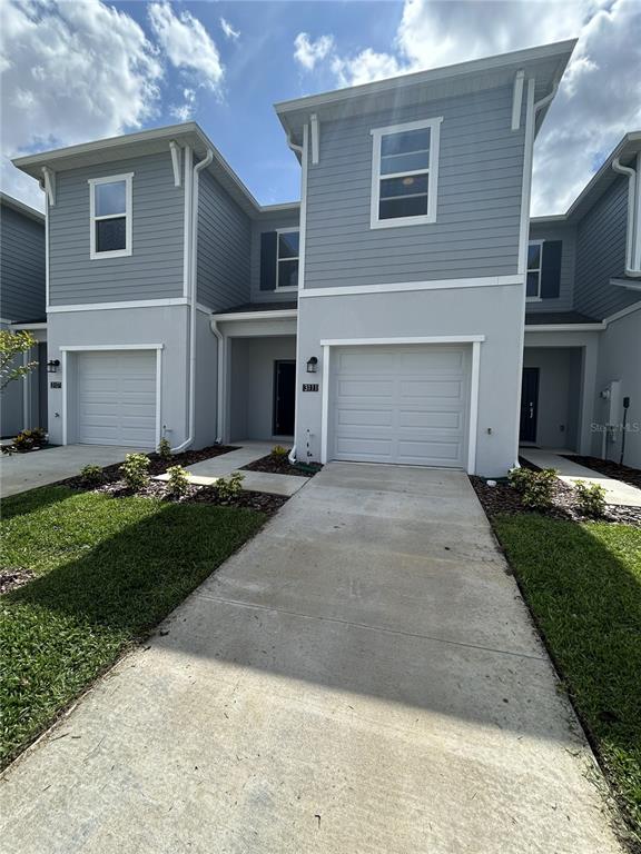 A two-story townhouse exterior features light blue siding, white trim, and a single-car garage — 3111 KURTZ TER, DAVENPORT, FL