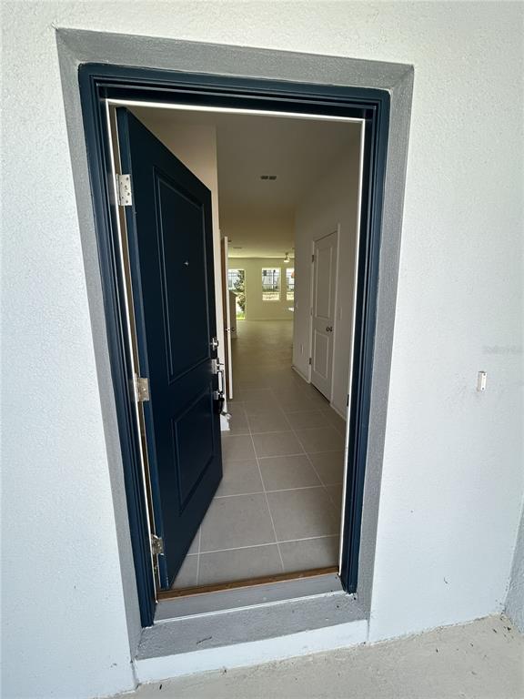 A dark blue front door opens into a tiled entryway leading to a bright interior — 3111 KURTZ TER, DAVENPORT, FL