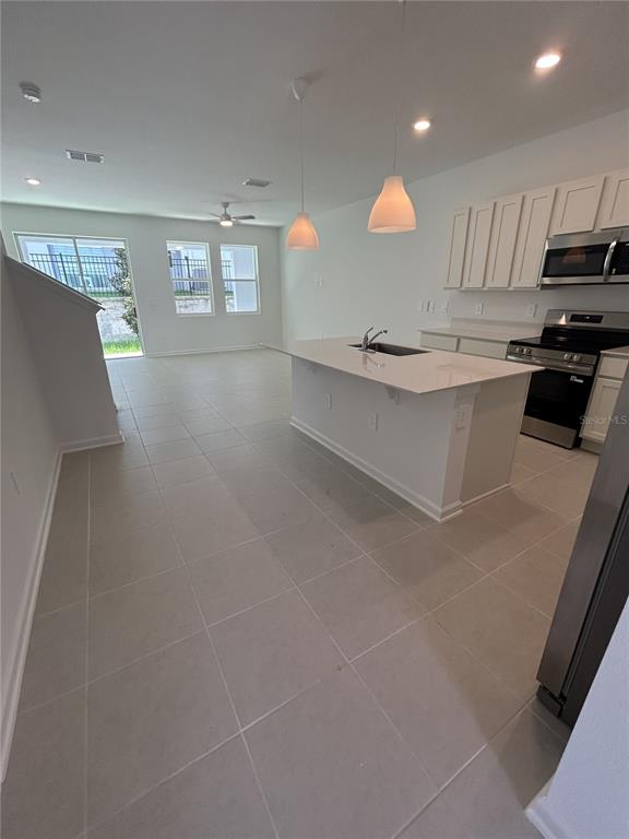 A kitchen with a white island and cabinets opens to a living area with tile floors — 3111 KURTZ TER, DAVENPORT, FL