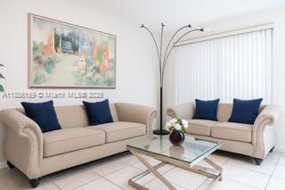 A living room features two beige sofas with blue pillows, a glass coffee table, and art — 255 Central Blvd, Miami FL 33144, MIAMI, FL