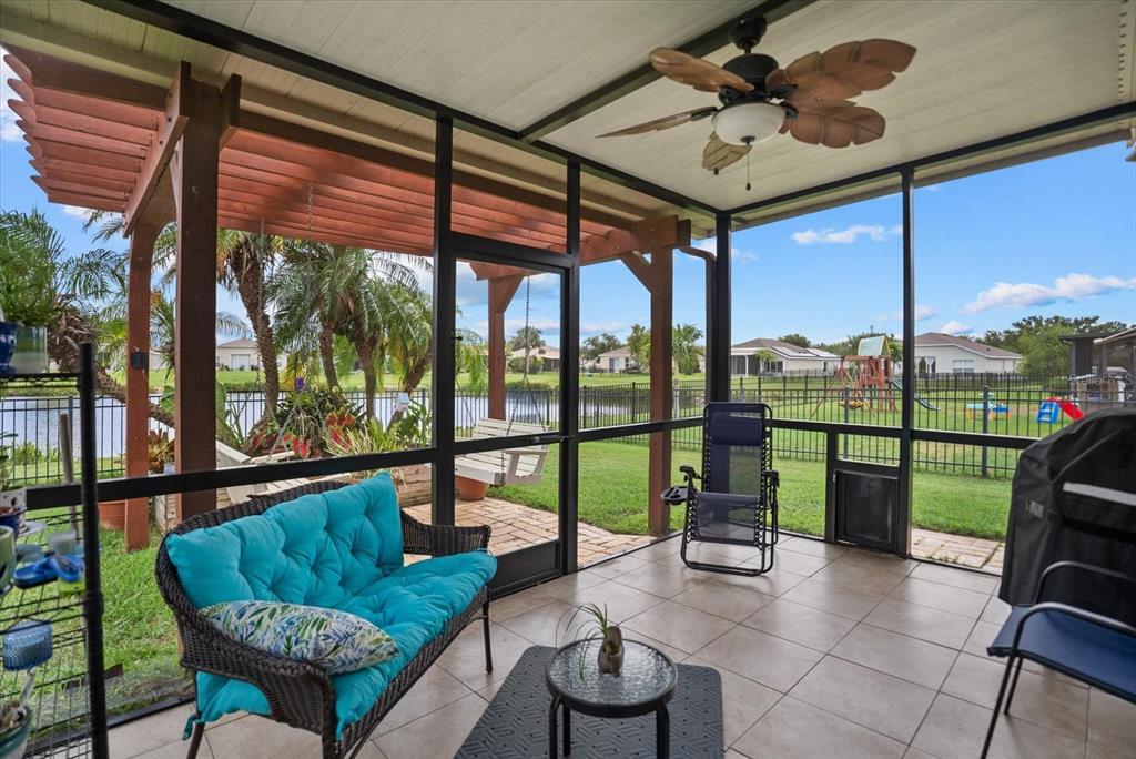 A screened-in porch with tile flooring, a ceiling fan, and views of a backyard pond — 5020 98TH AVENUE E, PARRISH, FL