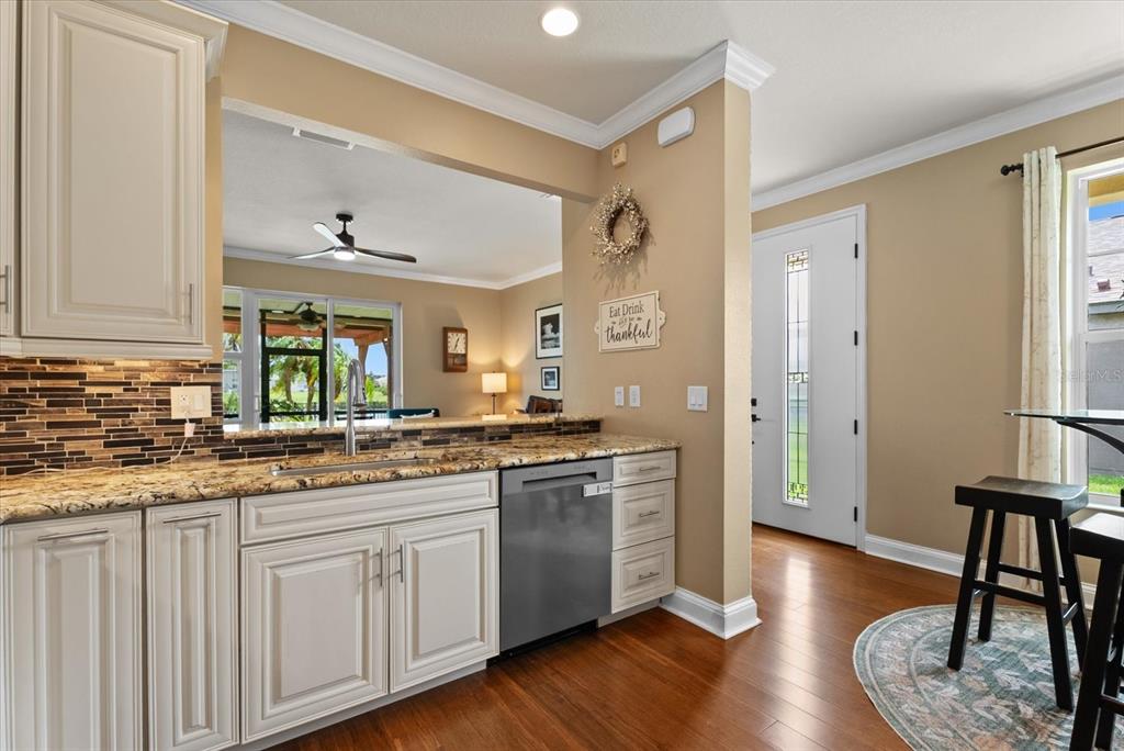 A kitchen features white cabinets, granite countertops, a stainless steel dishwasher, and hardwood flooring — 5020 98TH AVENUE E, PARRISH, FL